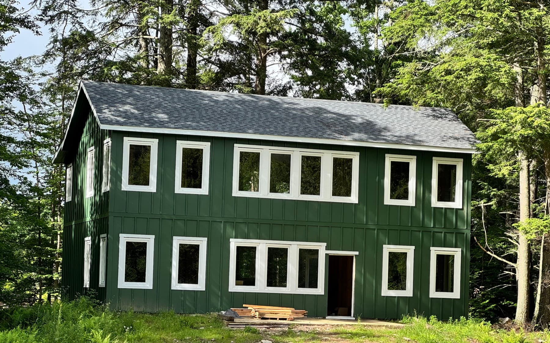 Finished two-story home clad in dark green board-and-batten siding after a single coat